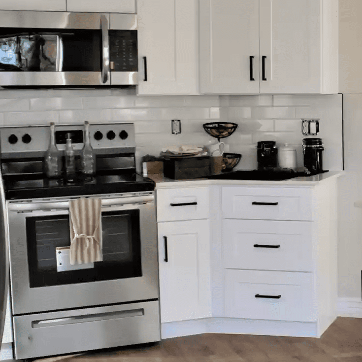 A kitchen with white cabinets and black counter tops.