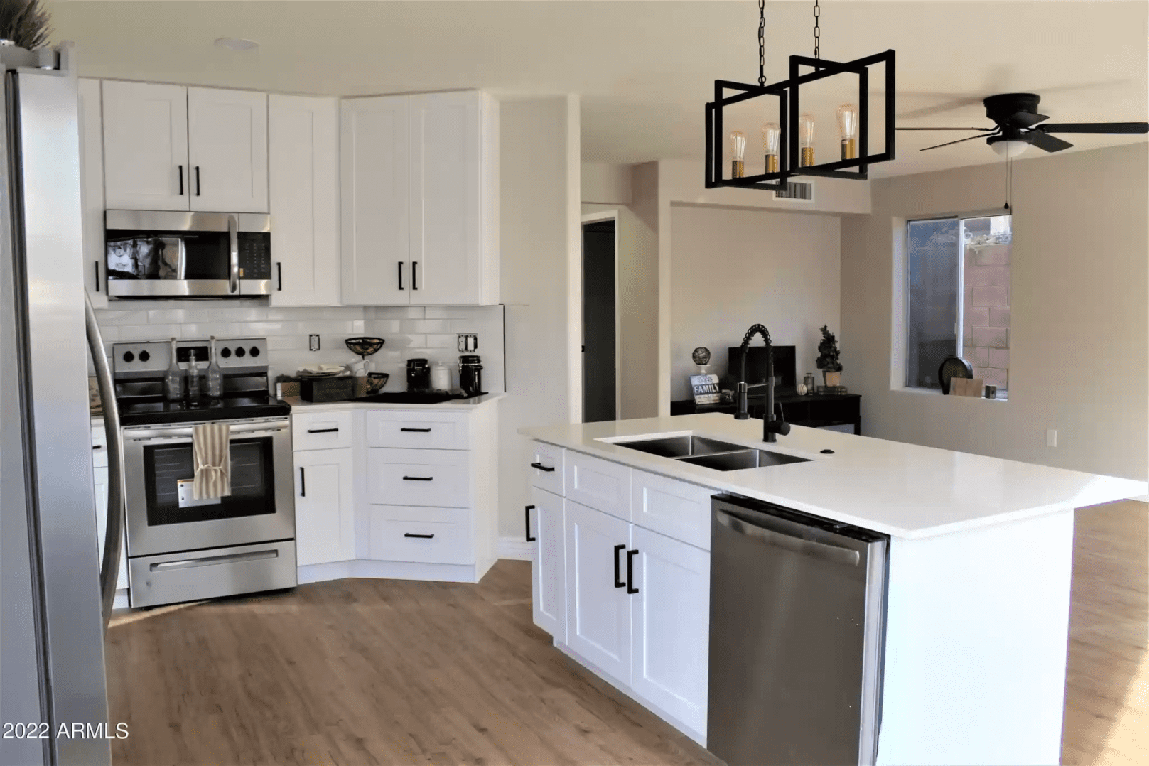 A kitchen with white cabinets and wood floors.