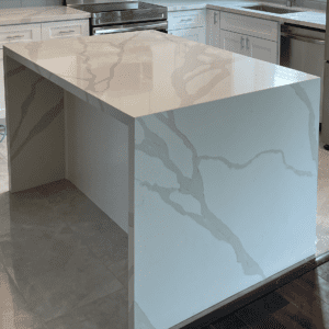 A kitchen with marble counter tops and white cabinets.