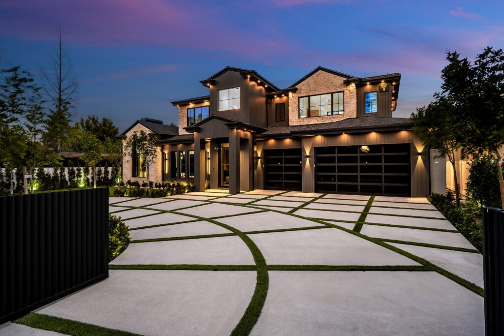Modern luxury house with a beautifully landscaped driveway at dusk.
